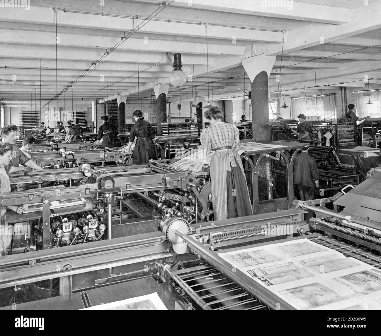 Giovani uomini e donne lavorano in una sala macchine in una casa di stampa berlinese. Foto Stock