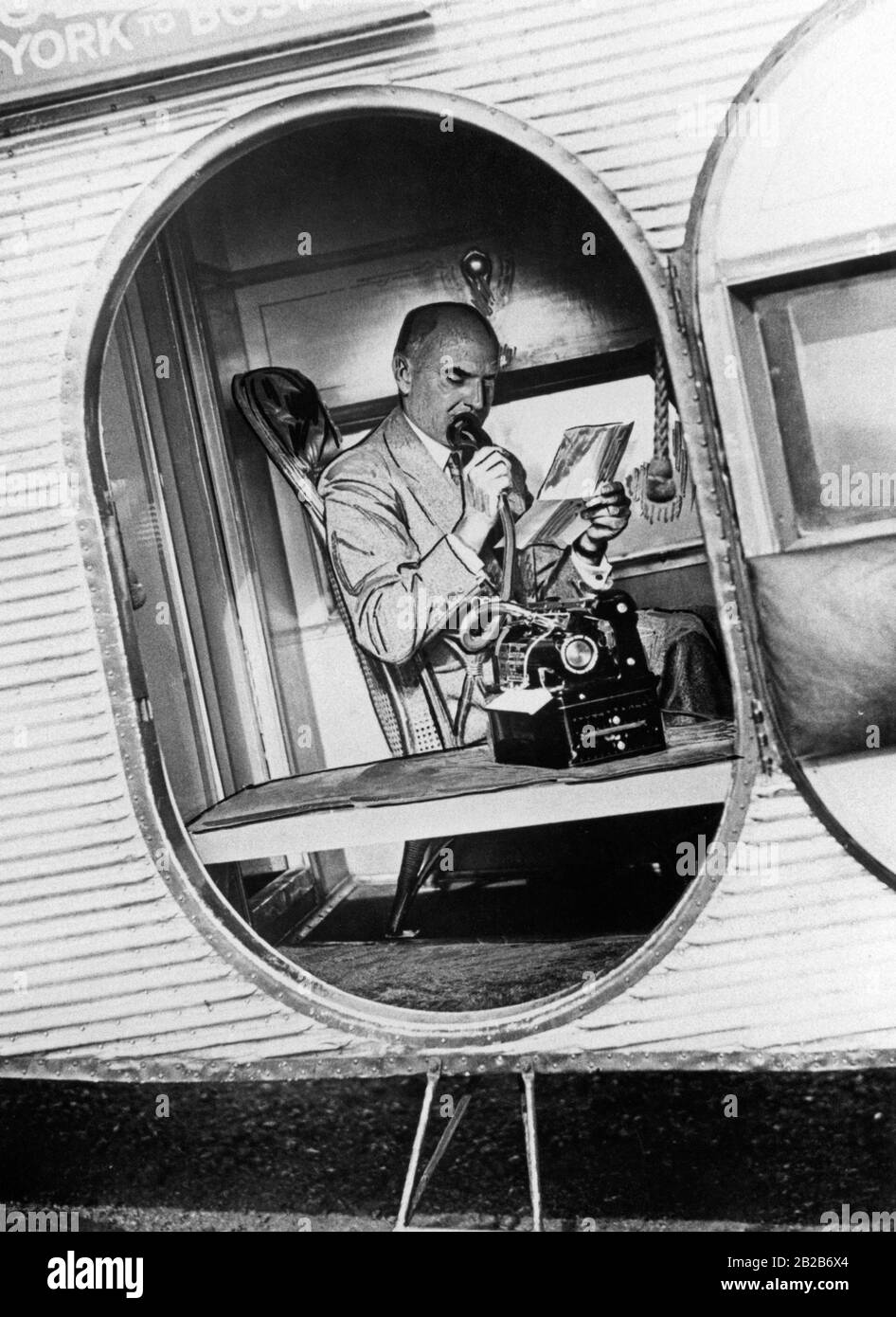 Un viaggiatore d'affari utilizza una moderna macchina per dettatura nell'aereo di una compagnia aerea americana durante un volo da Boston a New York. Foto Stock