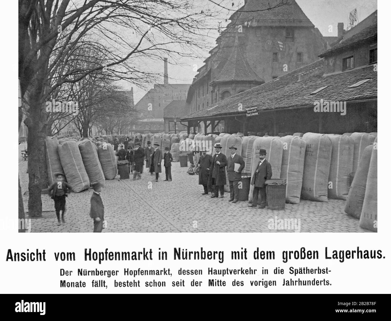 Vista del mercato del luppolo a Norimberga con il grande magazzino (a destra, con lo stemma della città di Norimberga su di esso) nell'autunno 1913, che era un importante centro commerciale per il luppolo in quel momento. I commercianti si trovano di fronte a grandi sacchi di luppolo con il raccolto fresco di fronte all'attività della commissione Franz Leberman. In background è una fabbrica di nome Bruell e Rein. Foto Stock
