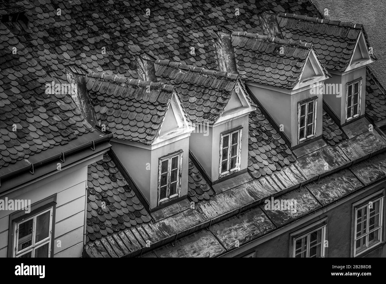 Finestre di dormitori su un tetto di piastrelle rosse in un edificio di Graz, la capitale dello stato federale della Stiria, Austria. Bianco e nero Foto Stock