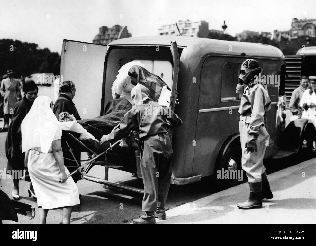 Dimostrazione della difesa civile in caso di raid aereo. Le persone ferite vengono trasportate dagli infermieri e dagli ordini della difesa civile. Indossano indumenti di amianto e maschere speciali. Foto Stock