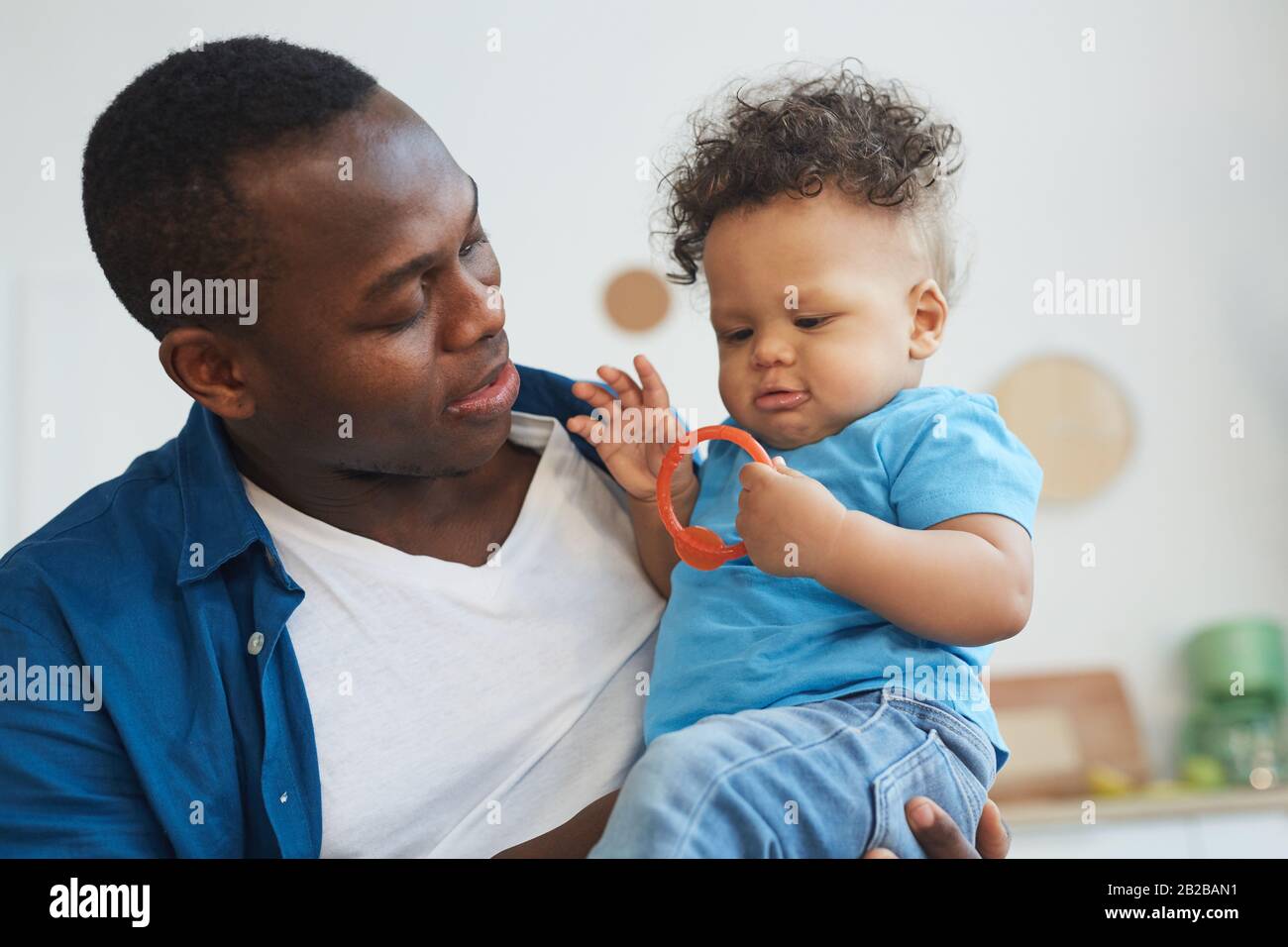 Ritratto di felice padre afro-americano che gioca con piccolo figlio mentre si siede in cucina interno Foto Stock