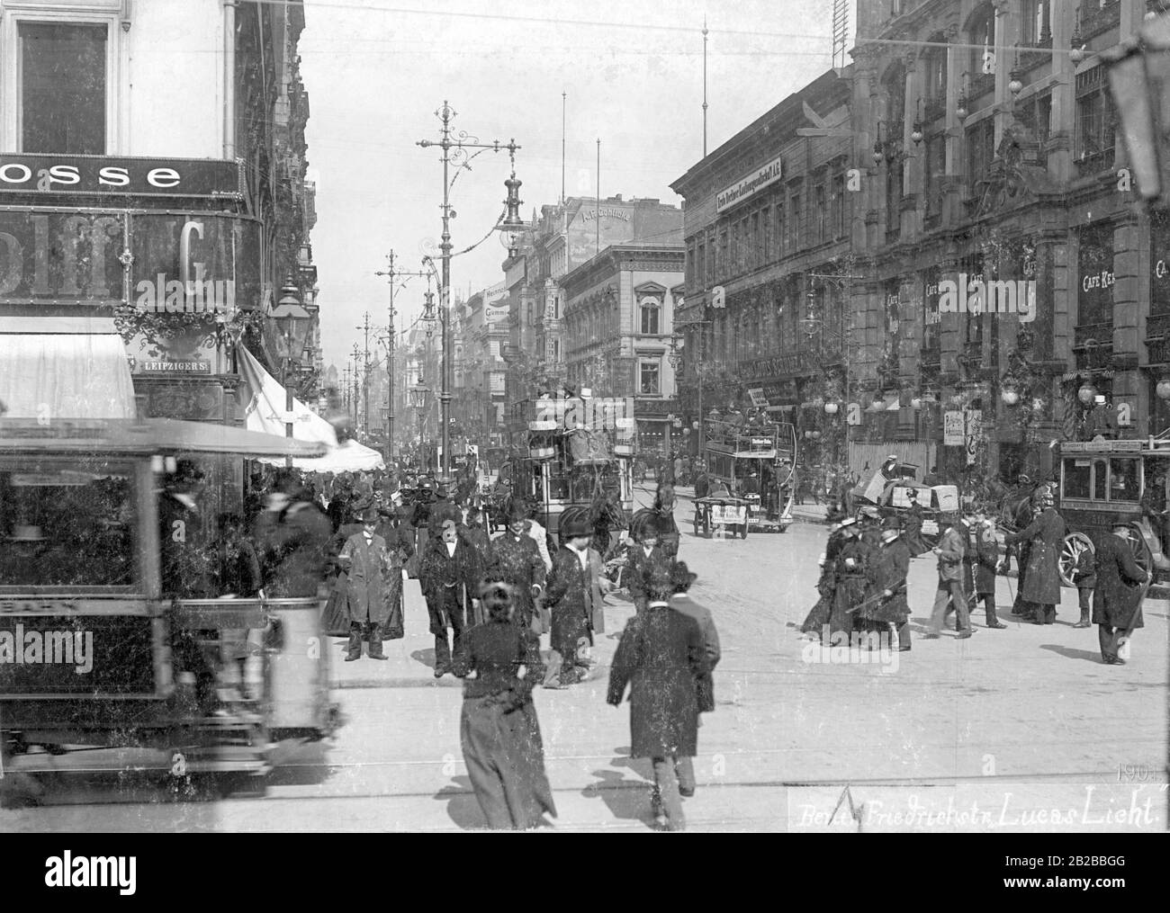 Una vista di Friedrichstrasse visto dall'incrocio con Leipziger Strasse. Ci sono molti passanti a piedi lungo la strada trafficata. Foto Stock