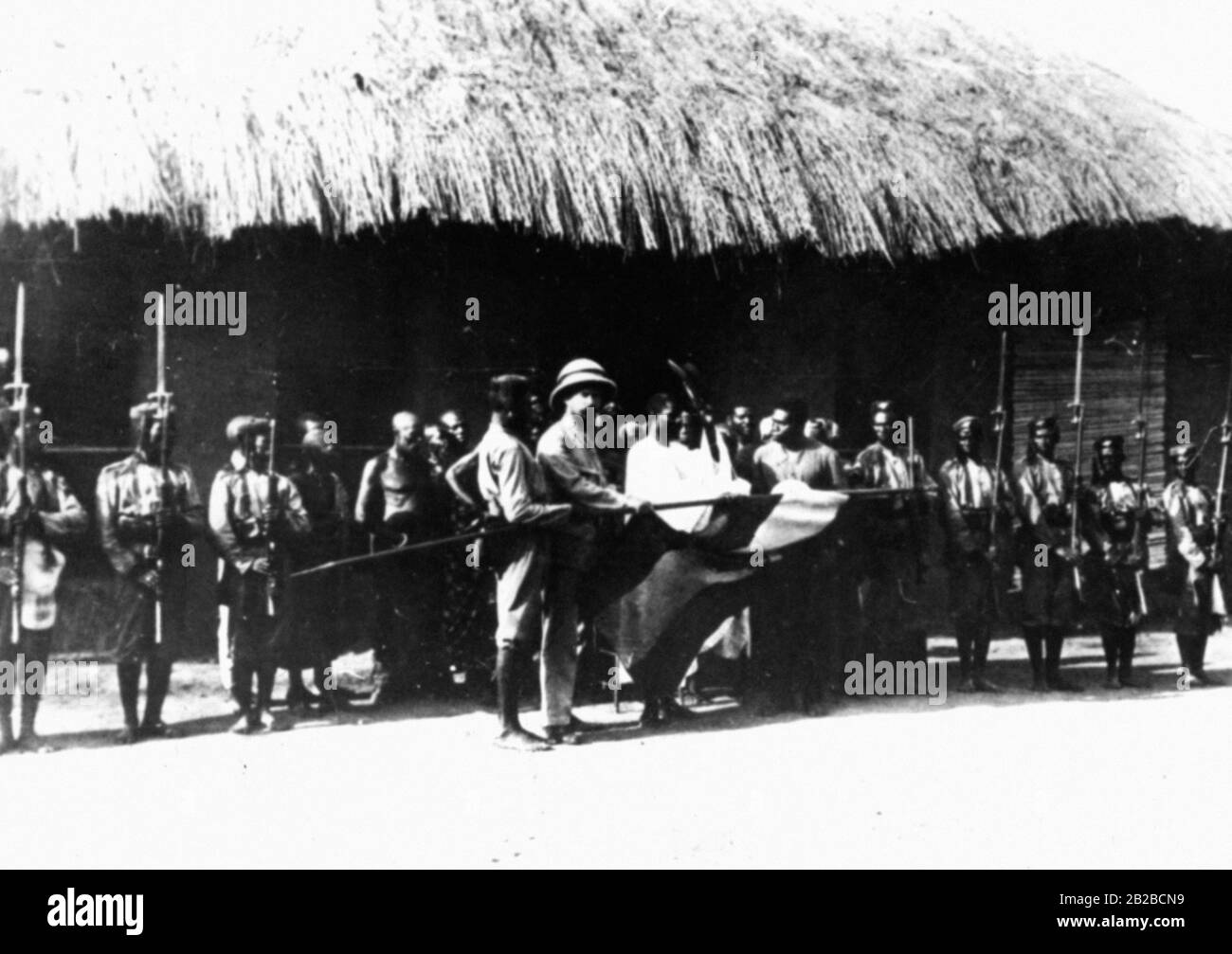 Un capo del Togo prende il giuramento di fedeltà alla bandiera tedesca alla presenza di un capo della stazione tedesca. Il capo è solennemente nominato e dato un cappuccio che serve come distintivo. Foto non ondulata. Foto Stock