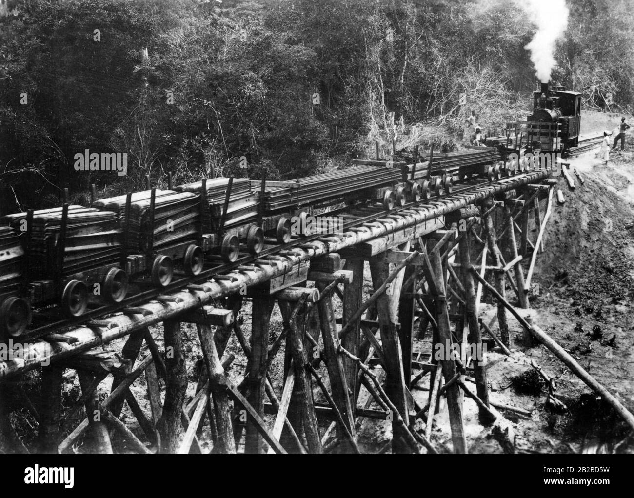 Una locomotiva spinge carri carichi di assi su un ponte di legno sulla  linea ferroviaria tra Dar es Salaam e Morogoro in Africa orientale tedesca  Foto stock - Alamy