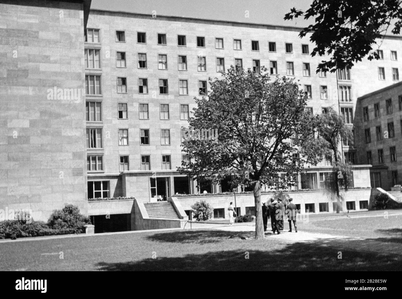 Vista della Cancelleria del nuovo Reich dal giardino. Gli SS camminano a destra dell'albero nel giardino verso l'edificio. Foto non ondulata. Foto Stock