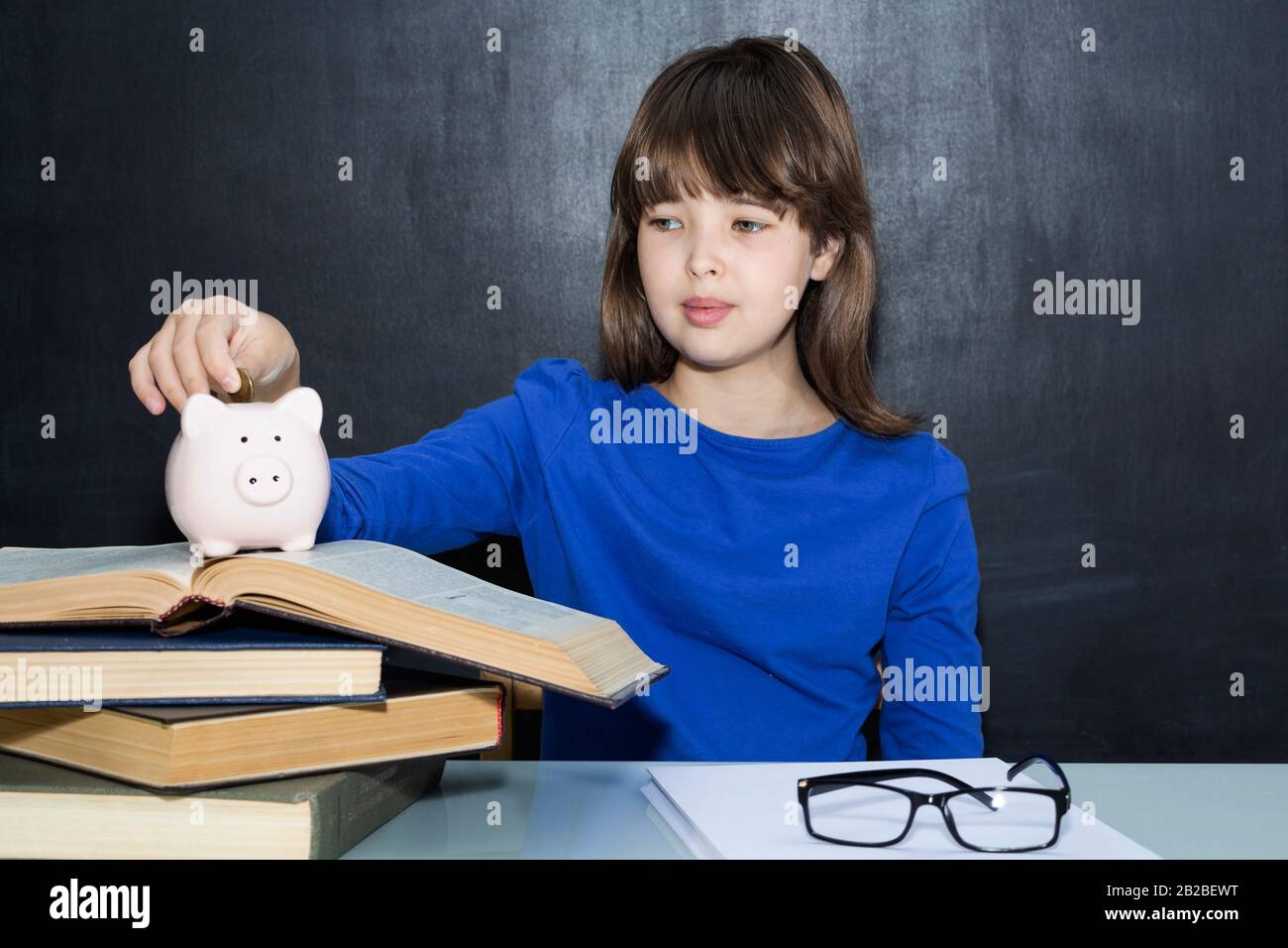 Teen mette le monete nella banca del piggy. Il concetto di istruzione a pagamento Foto Stock