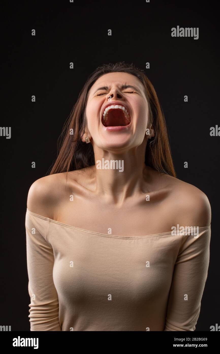 Ritratto di brunetta Donna urlante su sfondo nero Foto Stock
