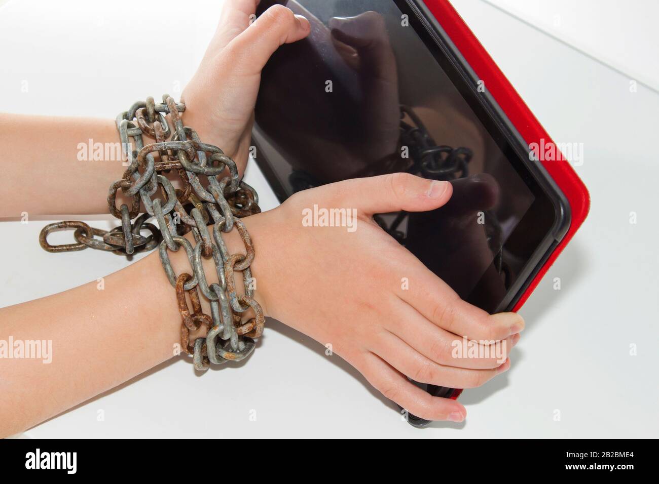 La catena del ferro unisce le mani e lo smartphone - concetto di dipendenza del telefono mobile Foto Stock