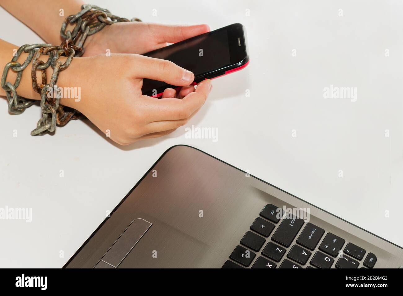 La catena del ferro unisce le mani e lo smartphone - concetto di dipendenza del telefono mobile Foto Stock