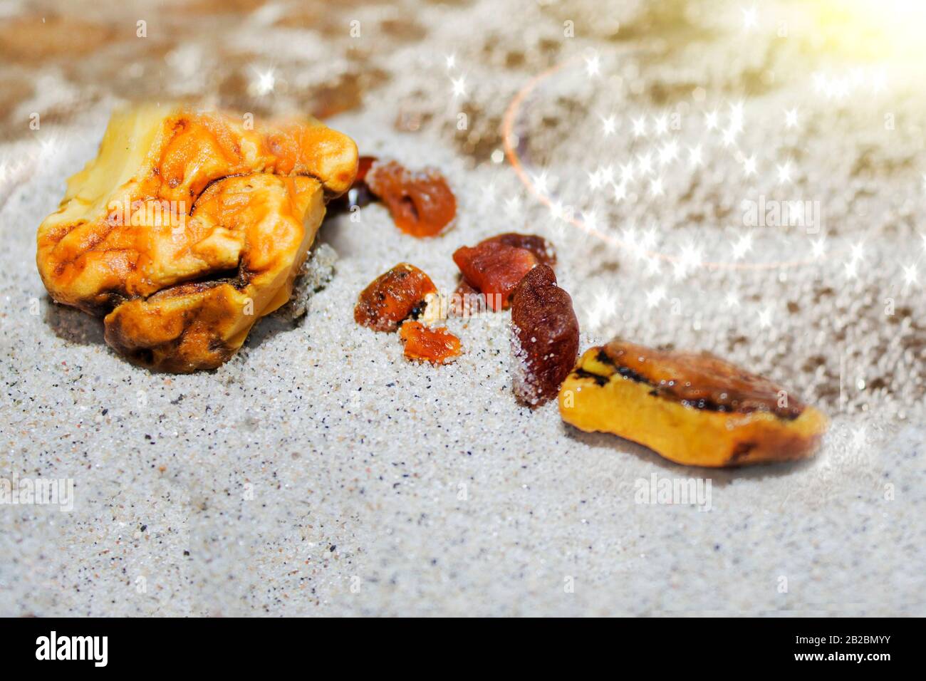 Ambra. I pezzi di ambra nella sabbia sulla spiaggia. Minerale naturale di pietra del sole sulla spiaggia. Amber Shine sulla spiaggia. Ambra sabbia baltica Foto Stock