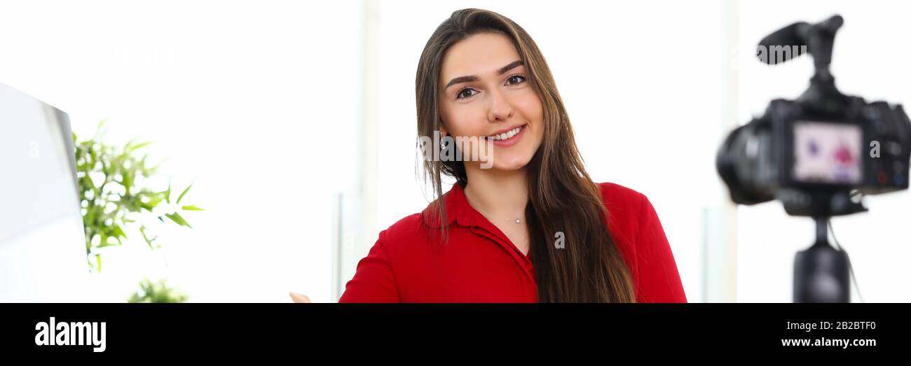 Giovane donna seduto in ufficio di fronte alla macchina fotografica sul treppiede Foto Stock