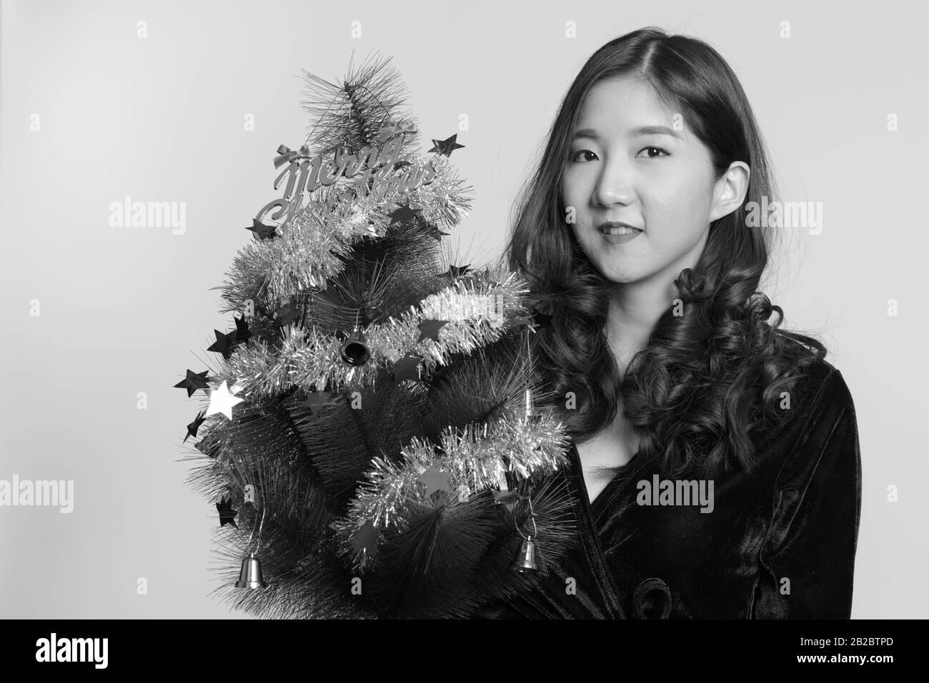 Felice giovane donna asiatica holding Merry Christmas tree Foto Stock