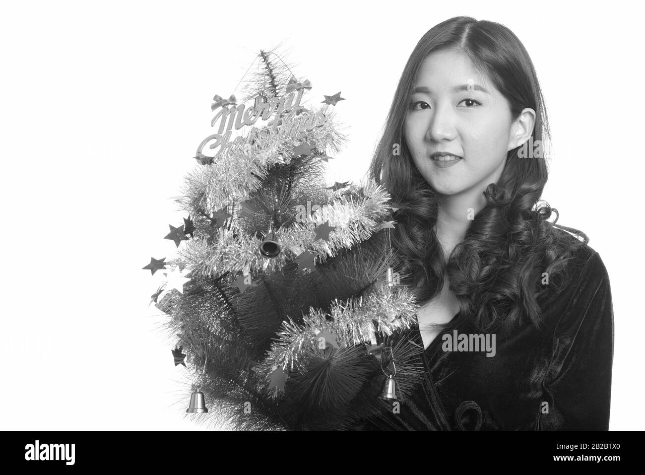 Felice giovane donna asiatica holding Merry Christmas tree Foto Stock