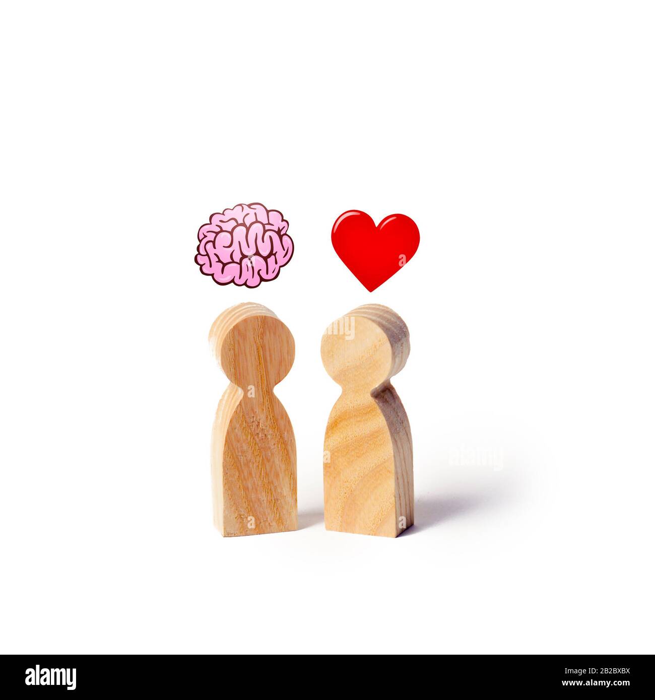 Due figure in legno con l'immagine del cervello e cuore. L'equilibrio tra amore e mente. La famiglia rispetto alla carriera o al lavoro. La psicologia della famiglia. Problema Foto Stock