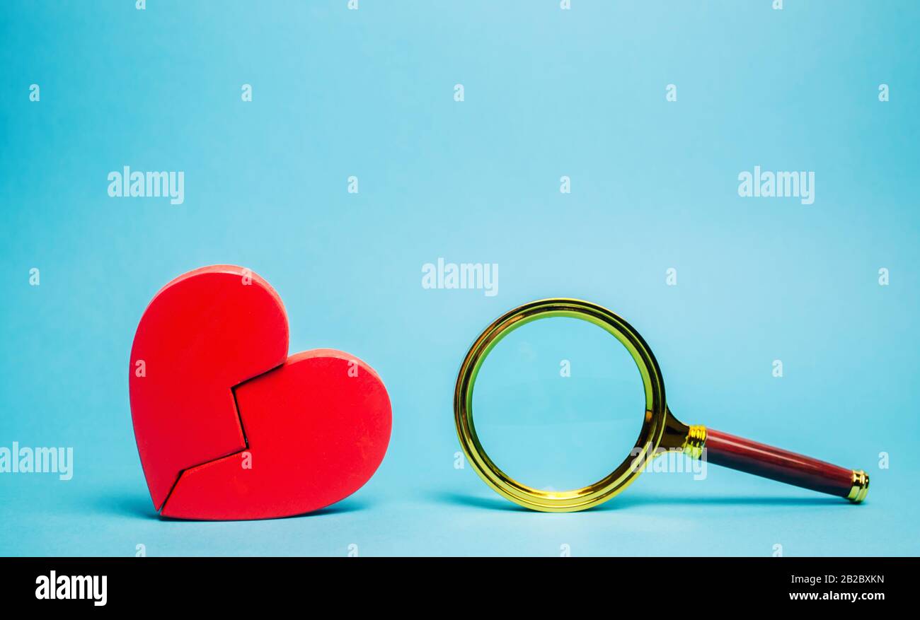 Cuore rosso e una lente d'ingrandimento. Il concetto di trovare amore e relazioni. Trova un compagno di anima. Solitudine. Servizi di psicologo di famiglia. San Valentino Foto Stock