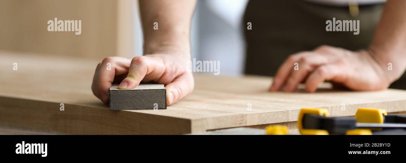 L'uomo falegname macina la lamiera di legno in officina Foto Stock