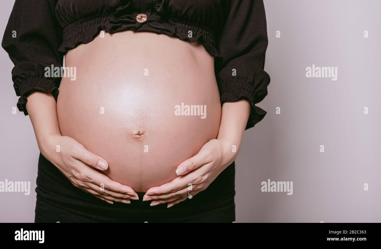 Gravidanza, maternità, persone e concetto di aspettativa, Ritagliato di donna incinta in piedi su sfondo bianco. Con spazio di copia per il testo. Foto Stock