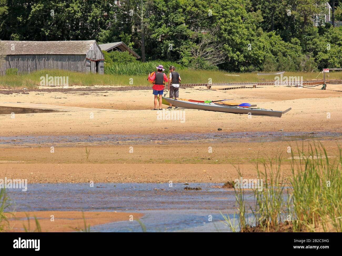 Due vogatori con la loro canoa tirato su sulla spiaggia Foto Stock