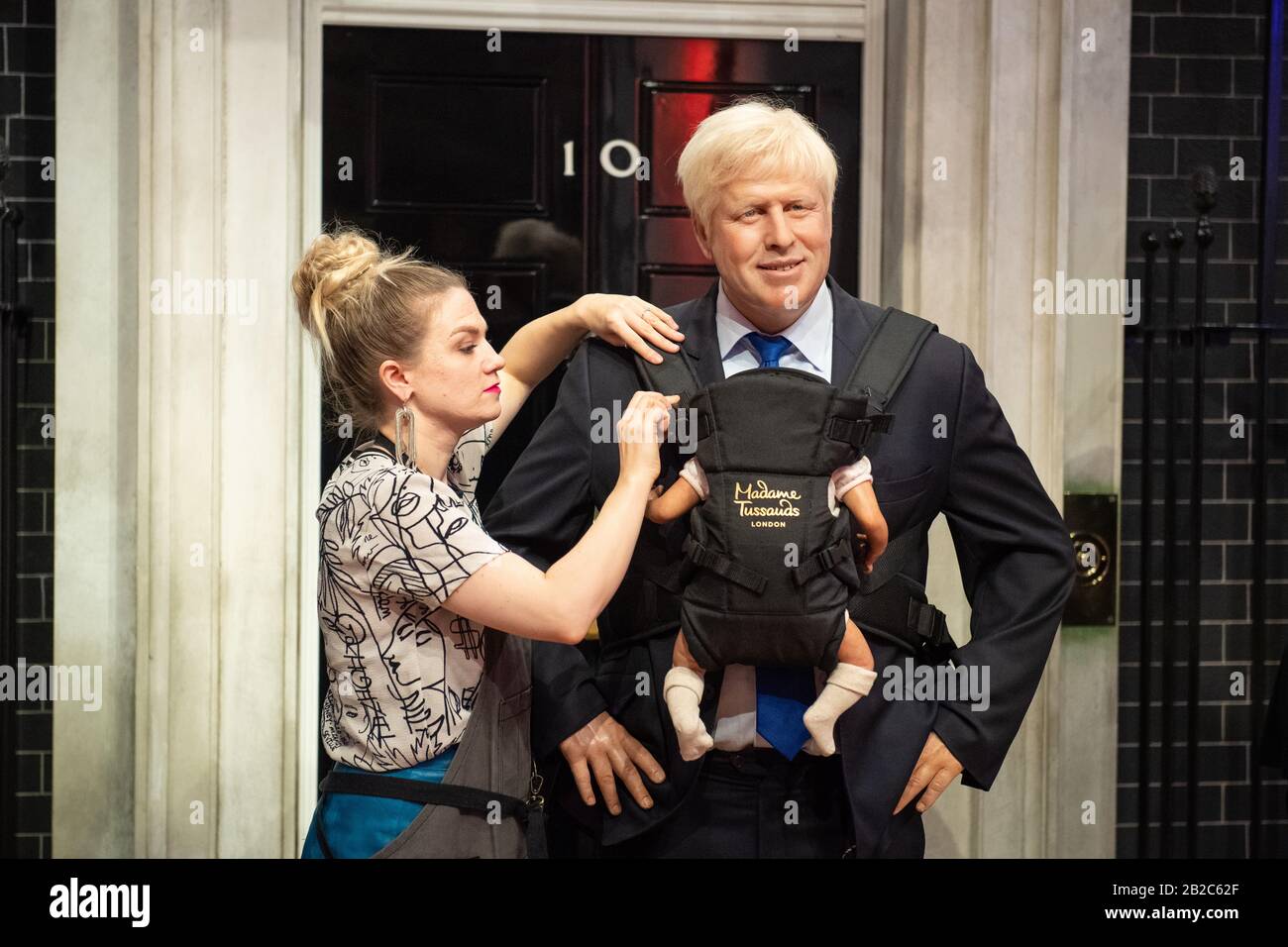 Un artista al Madame Tussauds di Londra si adatta al lavoro di lavoro del museo del primo ministro Boris Johnson con un baby carrier, a seguito del recente annuncio che si aspetta un bambino con il partner Carrie Symonds. Foto Stock