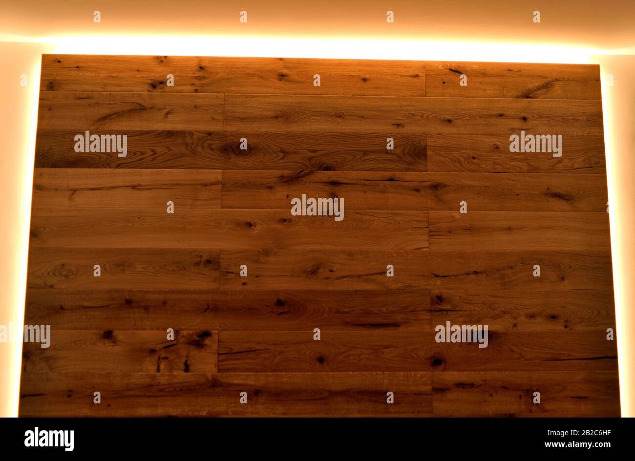 Un primo piano di una parete ricoperta di parquet con le sue vene naturali, delimitata da strisce LED. Foto Stock