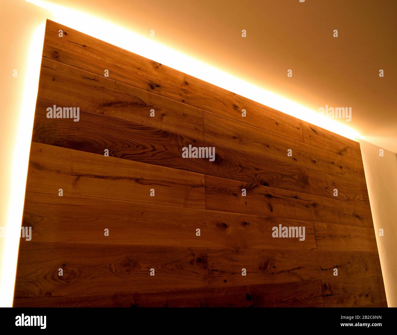 Un primo piano di una parete ricoperta di parquet con le sue vene naturali, delimitata da strisce LED. Foto Stock