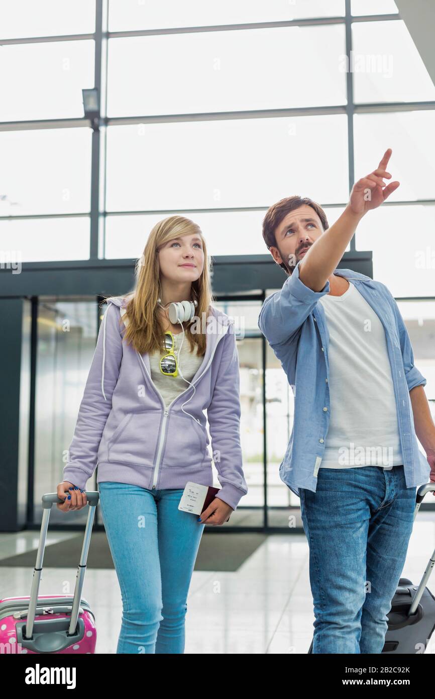 L'uomo maturo che arriva con la sua figlia in aeroporto che cerca il loro pick up Foto Stock