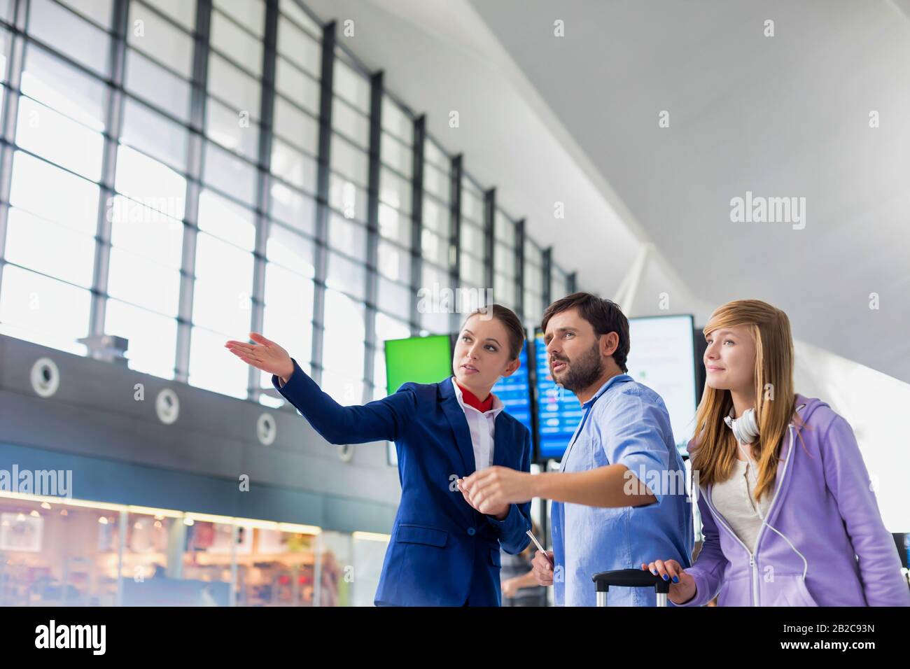 L'uomo maturo che viaggia con sua sorella mentre chiede assistenza al personale dell'aeroporto Foto Stock