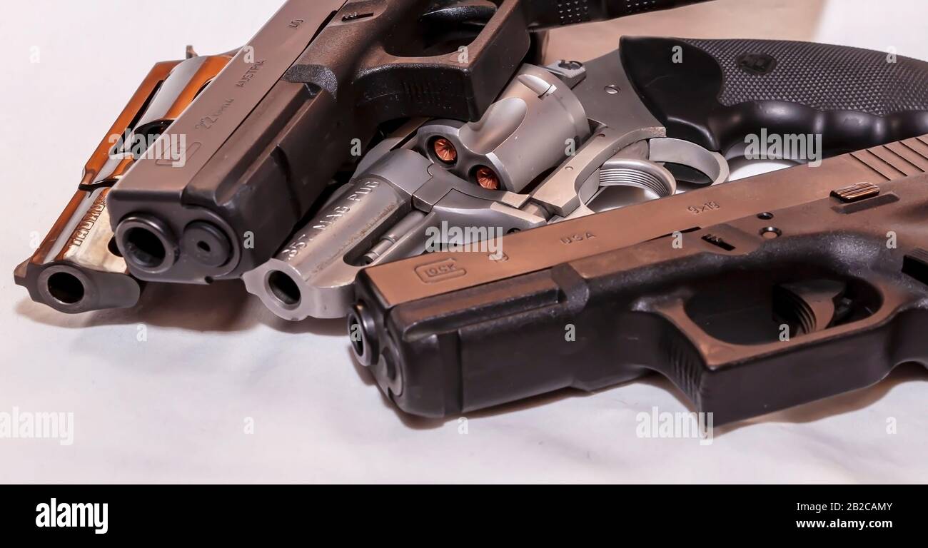 Quattro pistole, due serrature, 9mm e 40 calibro e due revolver, uno speciale Taurus 38 e un Charter Arm 357 Magnum su sfondo bianco Foto Stock