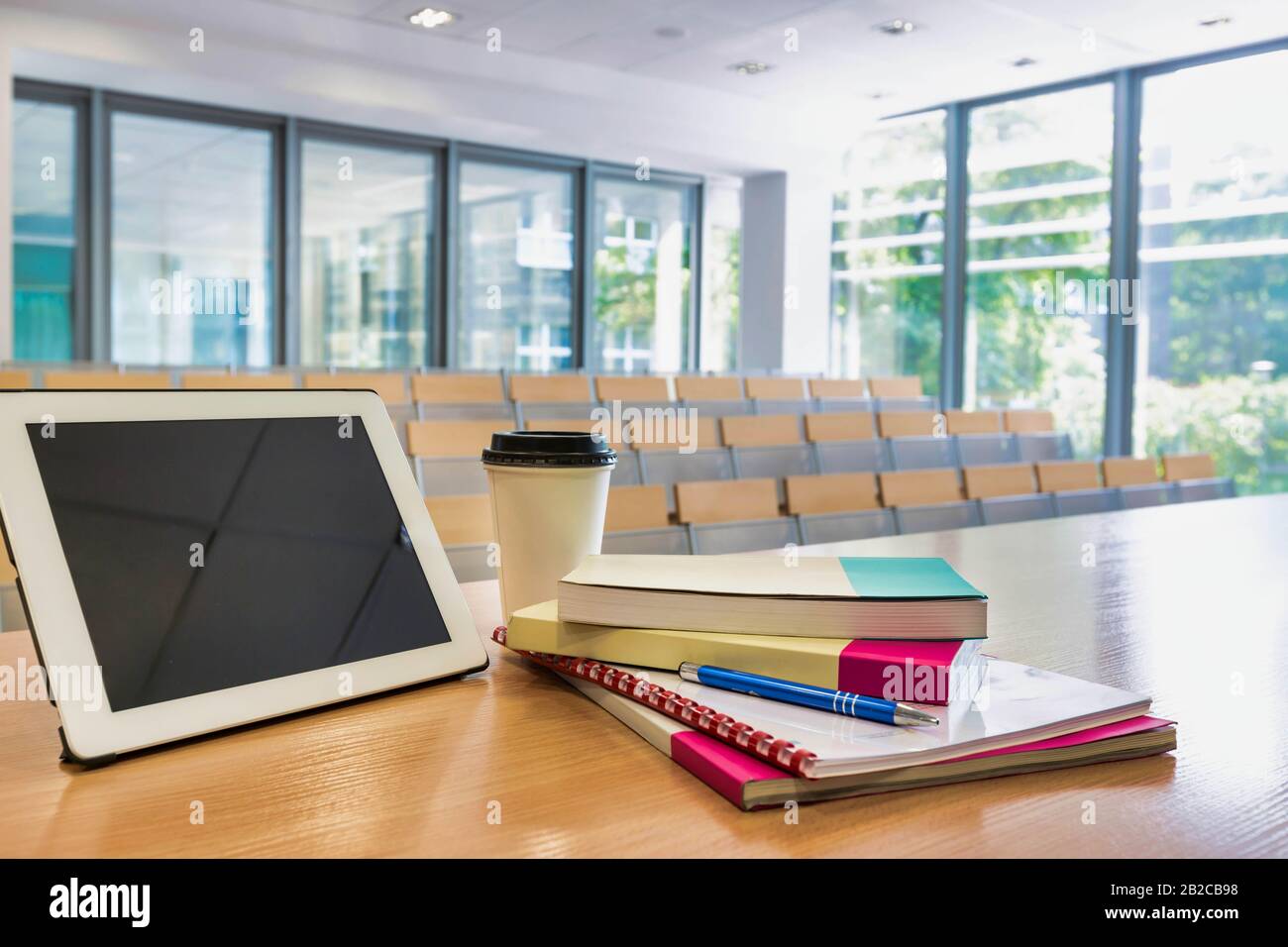 Foto di tablet digitali, libri e una tazza di caffè a tavola in classe Foto Stock