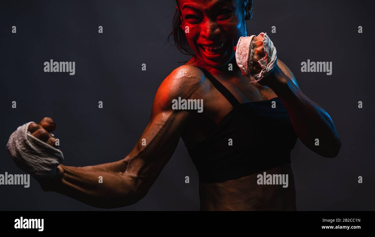 Primo piano di donne asiatiche heathly pugilato pugilato pugilato con muscolare fit tono corpo in rosa e blu neon su sfondo scuro parete, Foto Stock