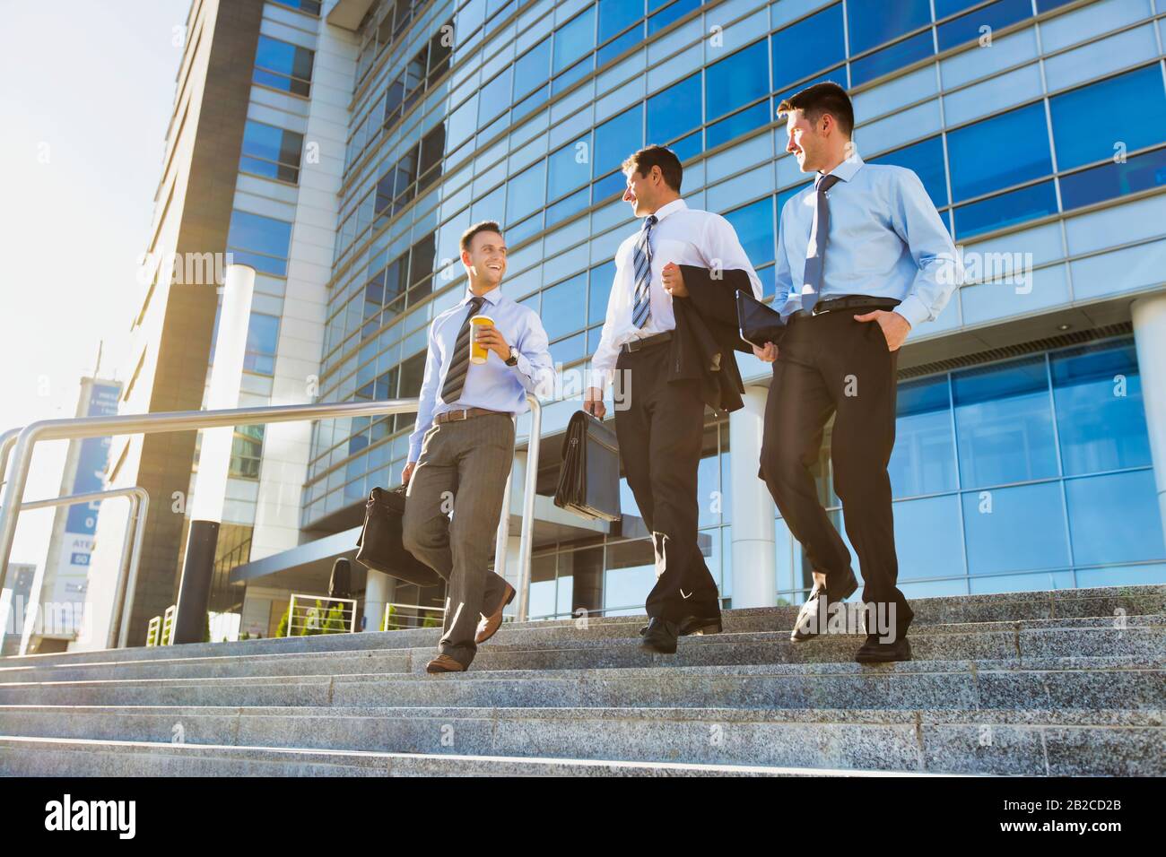 Uomini d'affari maturi che parlano mentre camminano sotto contro l'edificio dell'ufficio dopo il lavoro Foto Stock