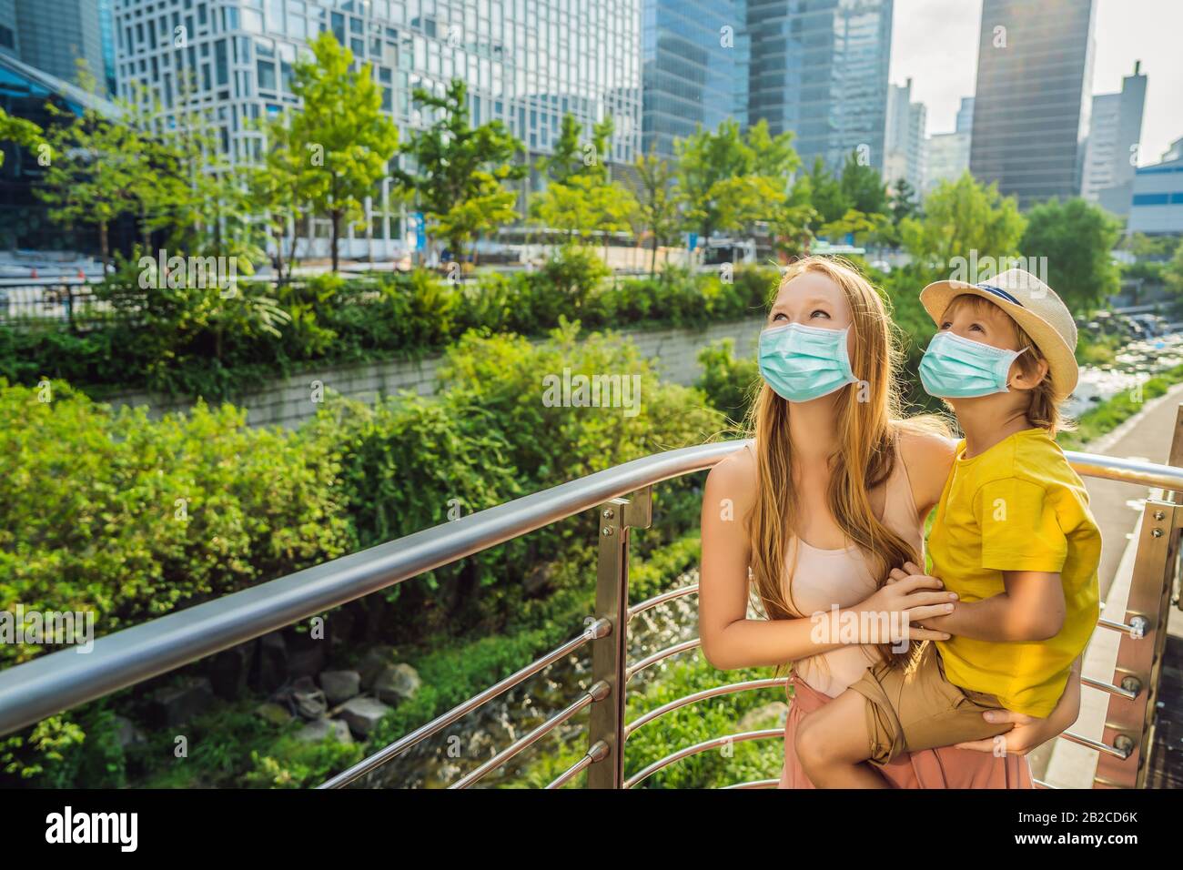 Mamma e figlio turisti in maschera medica a Cheonggyecheon ruscello a Seoul, Corea. Cheonggyecheon stream è il risultato di un massiccio progetto di rinnovamento urbano Foto Stock