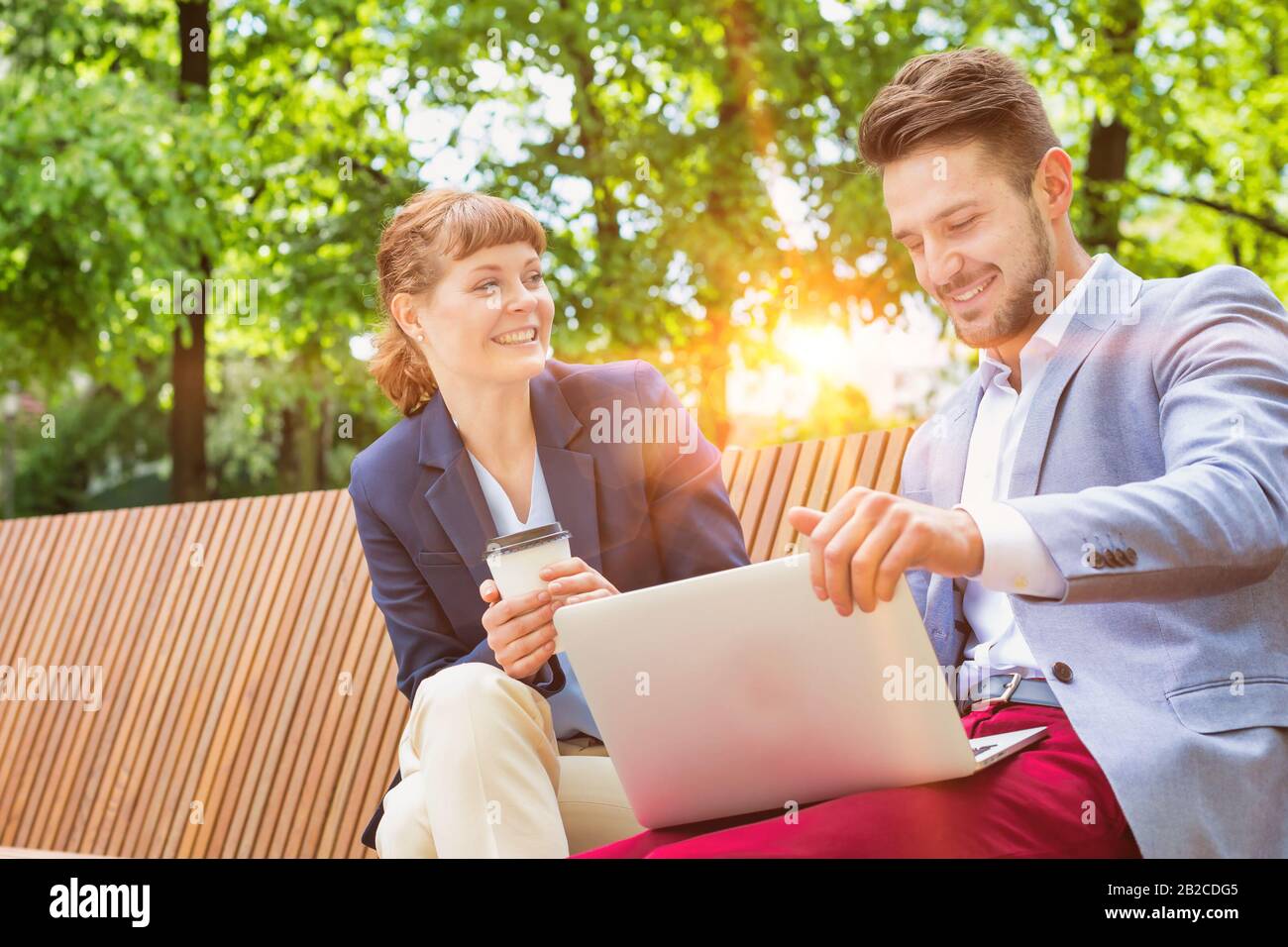 Uomo d'affari che discute i programmi sopra il laptop con businesswoman bello mentre seduto sul banco Foto Stock