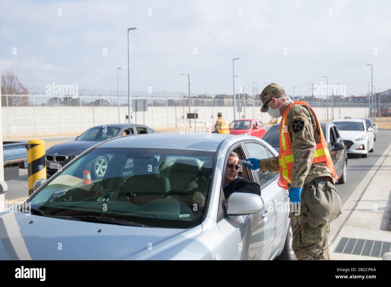 Un soldato statunitense scherma i passeggeri per il COVID-19, utilizzando un termometro presso un cancello d'ingresso per i militari della Garrison Humphreys, 27 febbraio 2020 a Pyeongtaek, Corea del Sud. Lo scoppio del nuovo coronavirus nella Corea del Sud è secondo solo alla Cina. Foto Stock