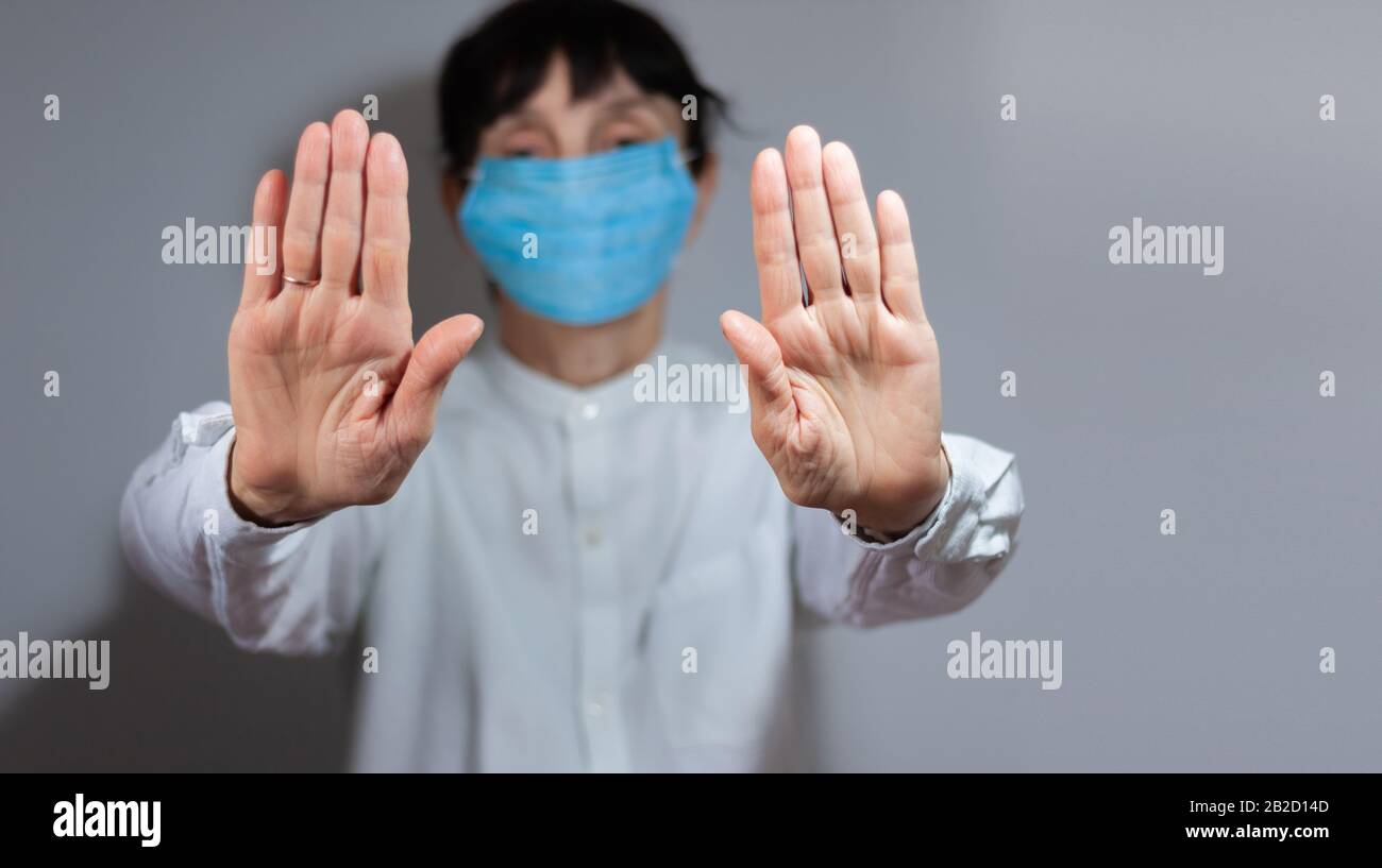 Arrestare la quarantena del coronavirus e il concetto di inquinamento atmosferico pm2.5. Donna anziana malata che indossa maschera respiratore per proteggere con braccio allungato. Wuhan, Cina ep Foto Stock