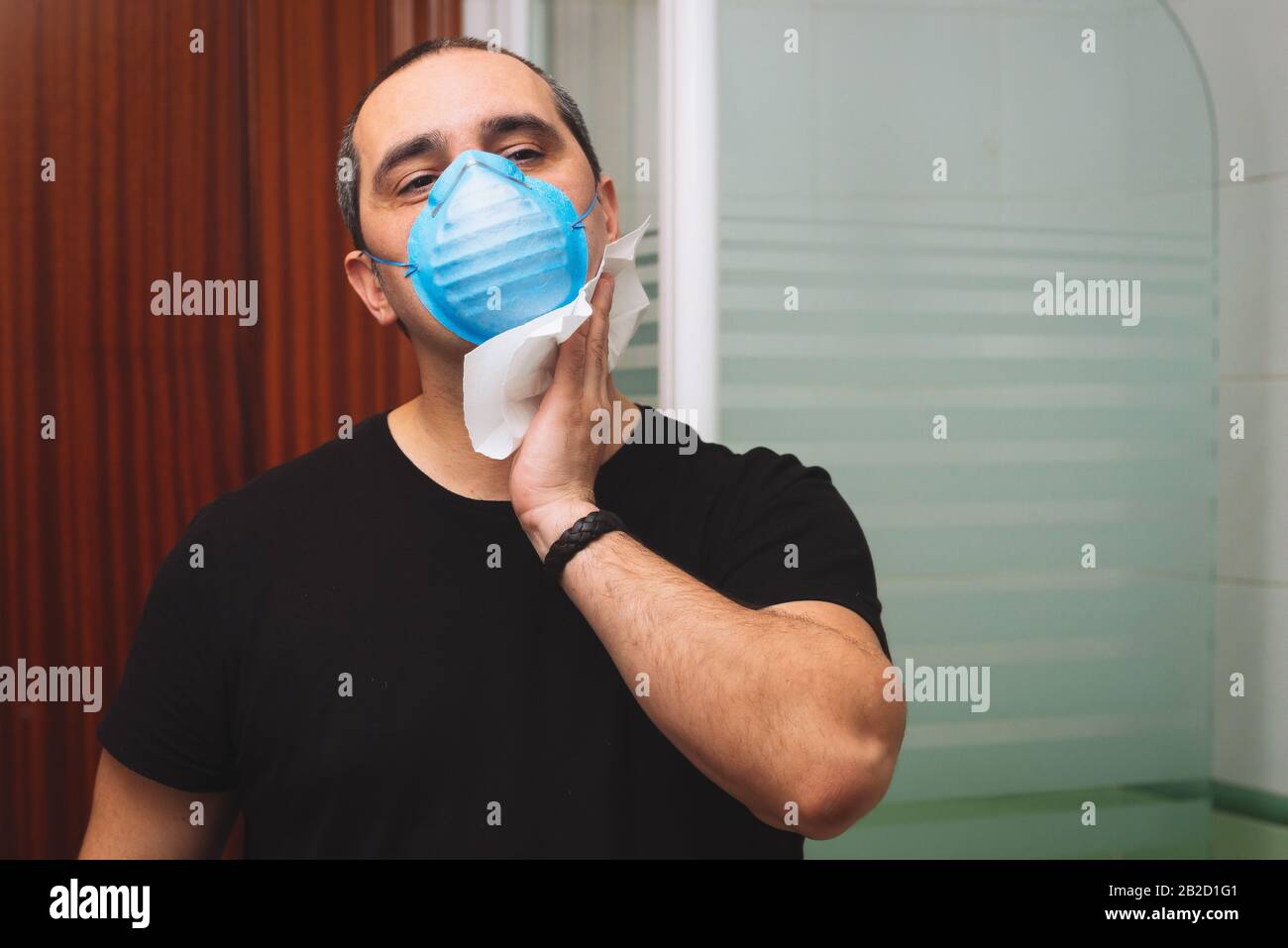 40s uomo con maschera medica pulisce il sudore sul suo viso Foto Stock