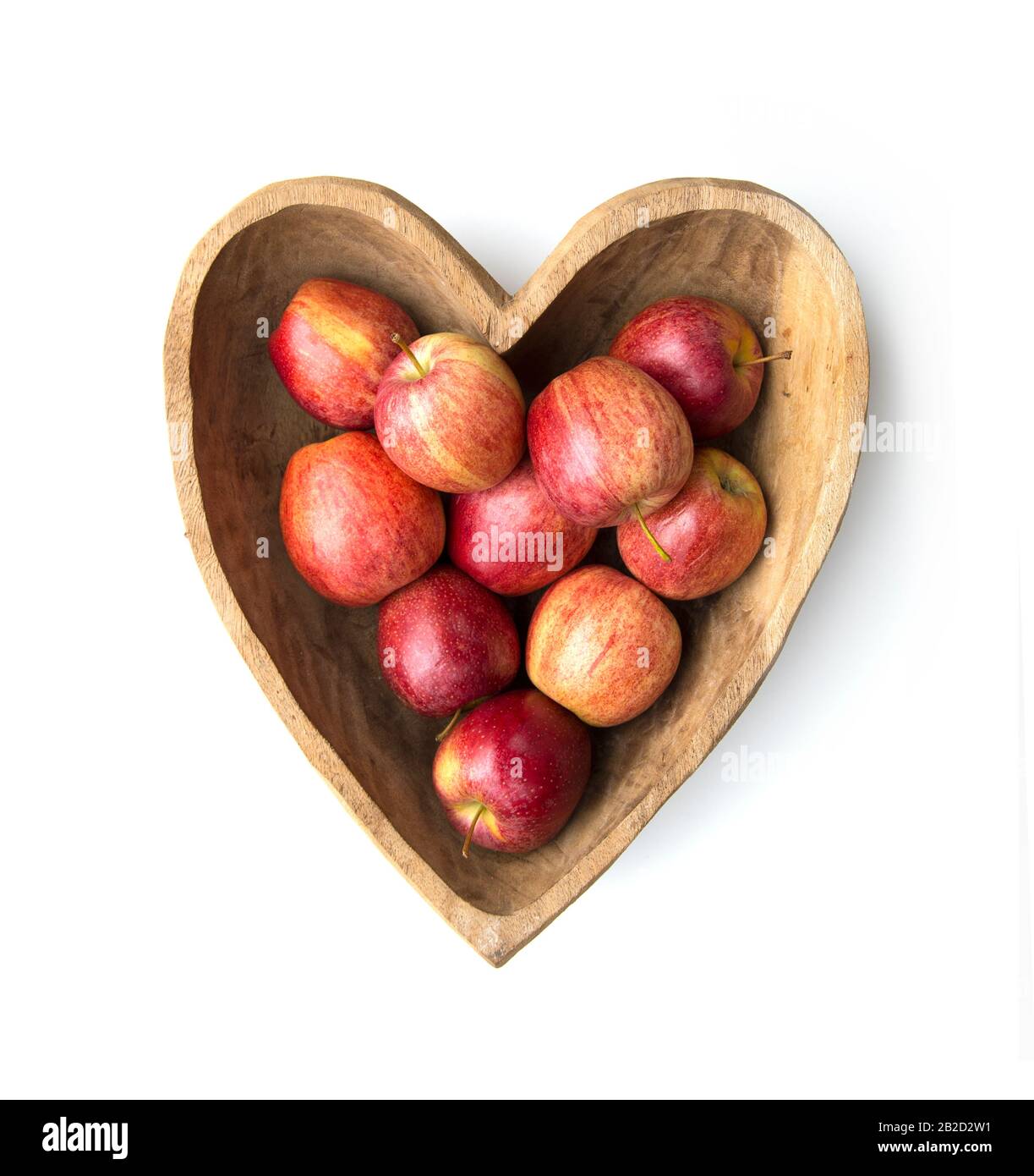 Ciotola a forma di cuore in legno con mele rosse Foto Stock