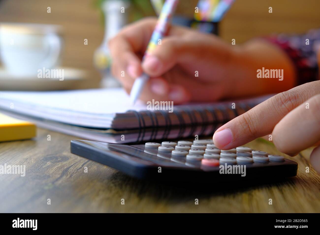 Primo piano di donne mano uso calcolatrice e scrittura Foto Stock