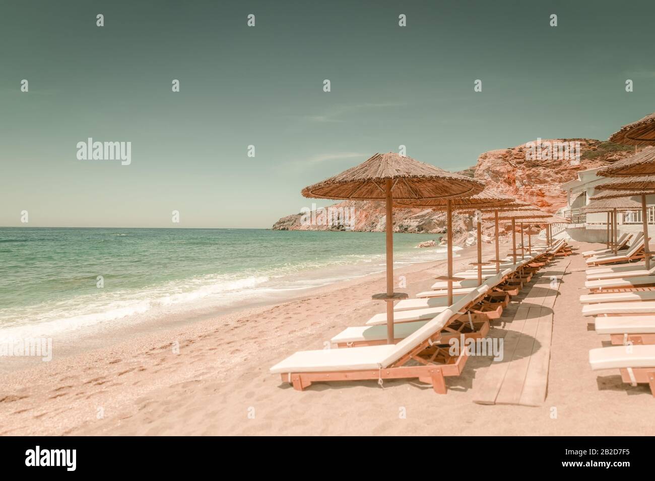 Incredibile paesaggio di spiaggia sabbiosa con sedie per il relax e ombrelloni nella giornata di sole. Isola di MILOS sul Mar Egeo. Grecia. Vacanza in paradiso concetto Foto Stock