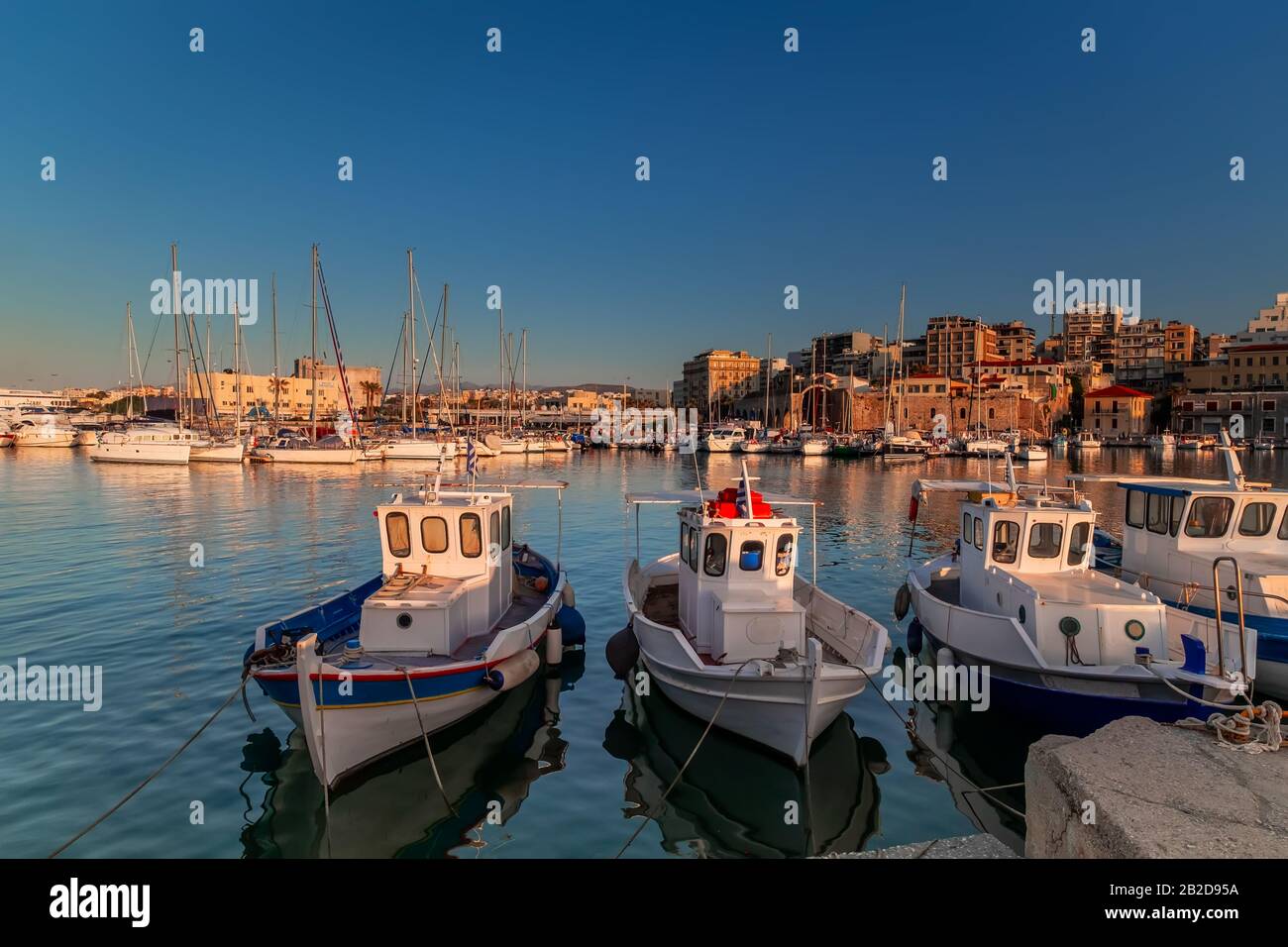 Vista panoramica del bellissimo tramonto nella fortezza di Koules (Rocca a Mare), isola di Creta. Barche che riflettono nello specchio d'acqua vicino al vecchio porto veneziano Foto Stock