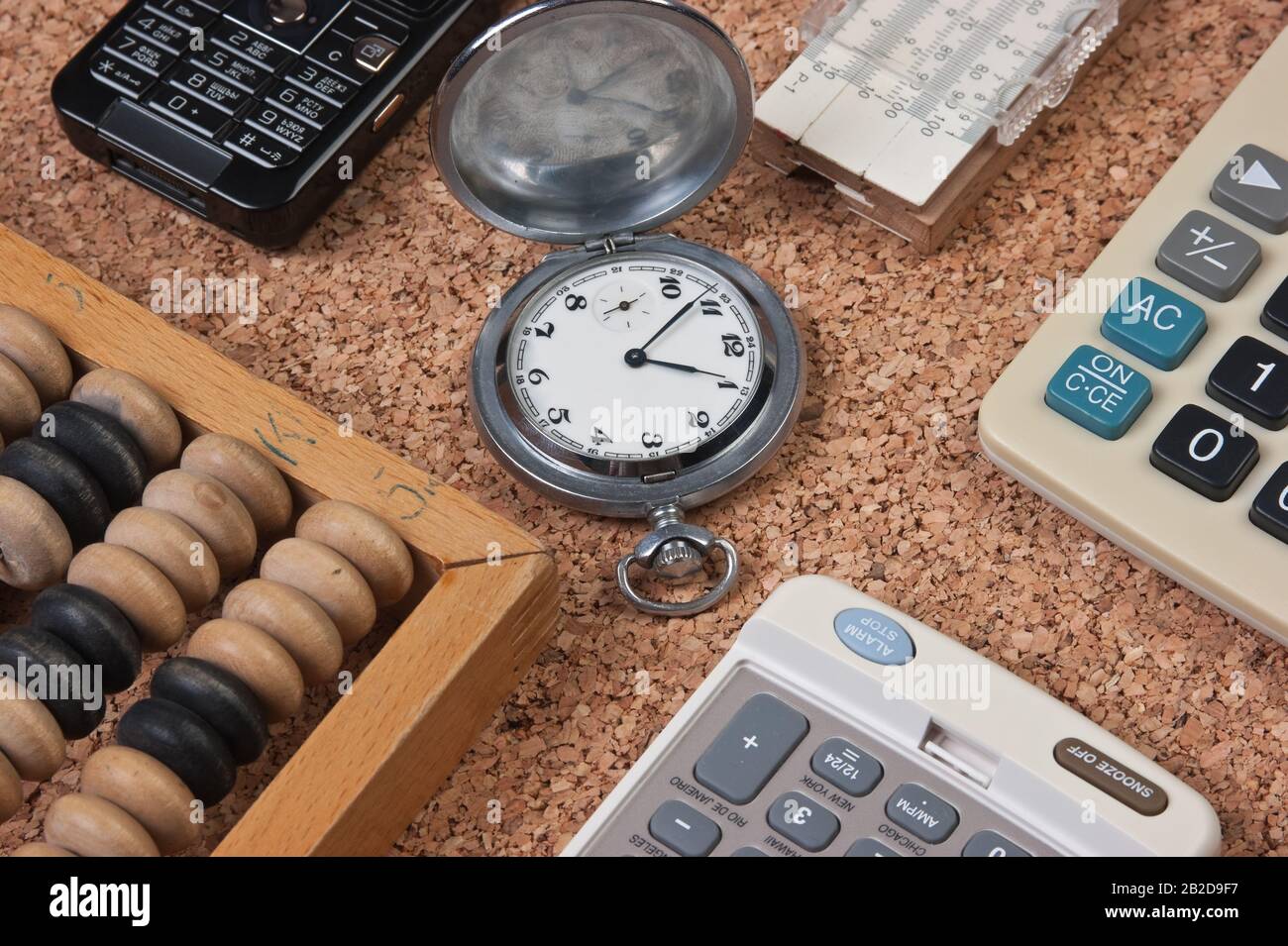 orologio tascabile, calcolatrice, abaco in legno e regola di scorrimento su  una tavola di sughero Foto stock - Alamy