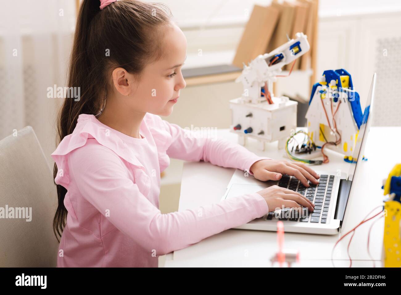 Ragazza intelligente programmazione e costruzione robot in dopo la classe scolastica Foto Stock