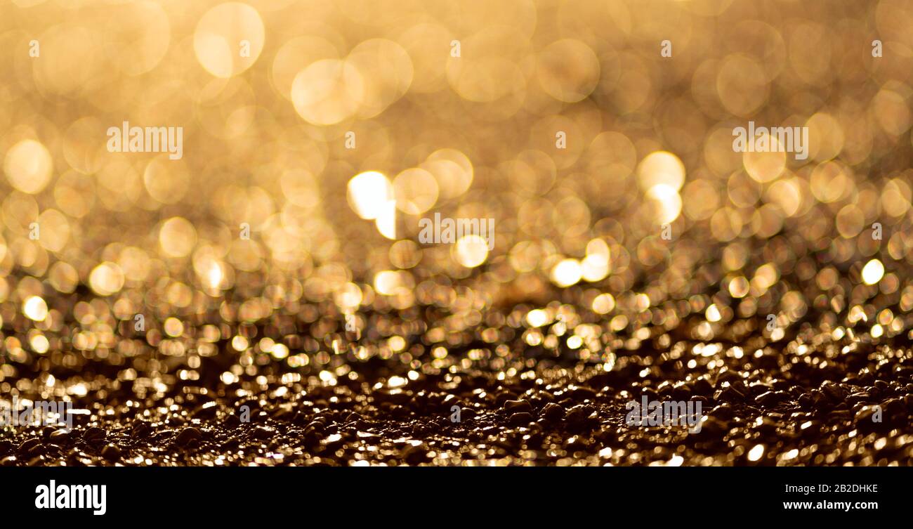 Luce brillante boke Blur. Ciottoli di mare. Sfondo di particelle di glitter dorato. Foto Stock