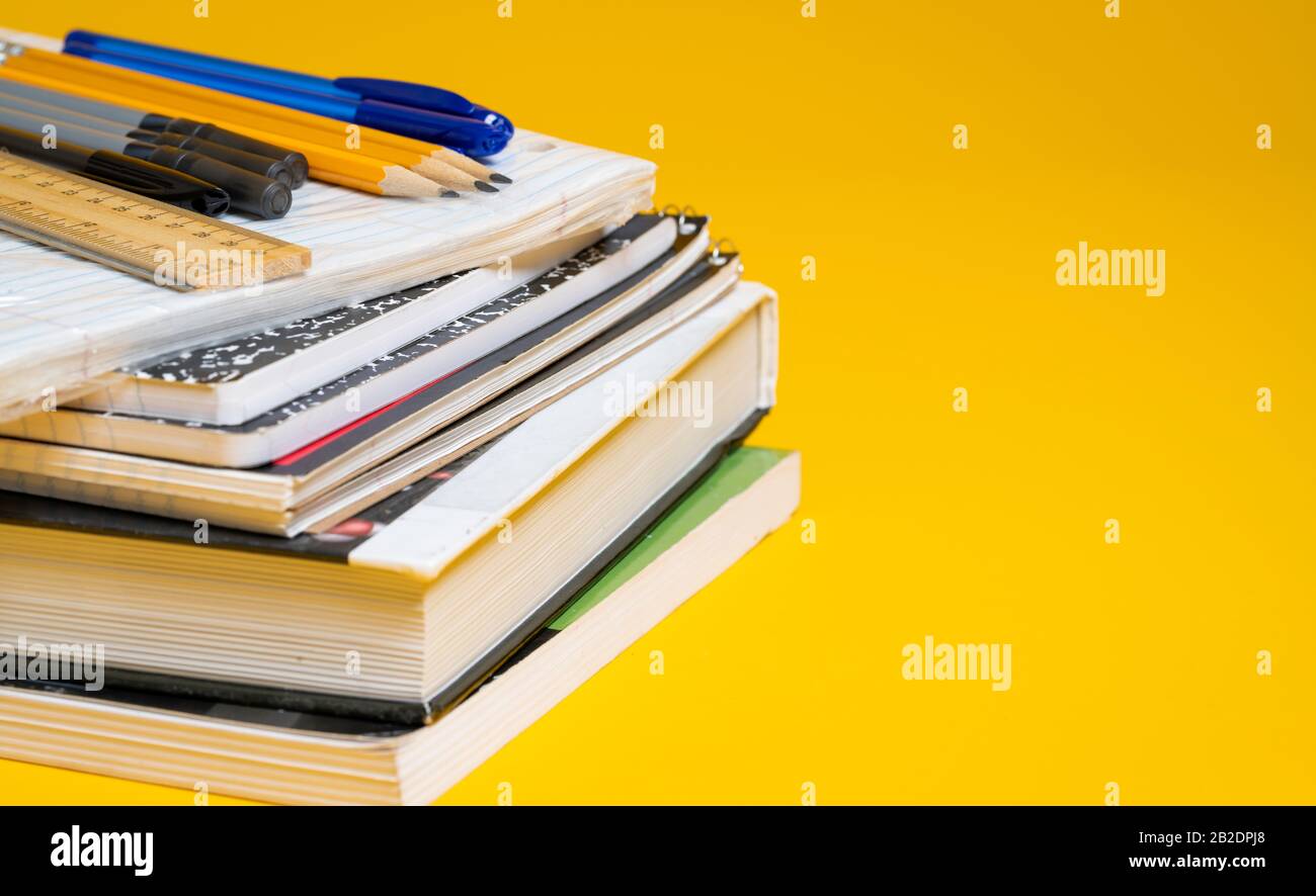 Libri scolastici e forniture su sfondo giallo Foto Stock