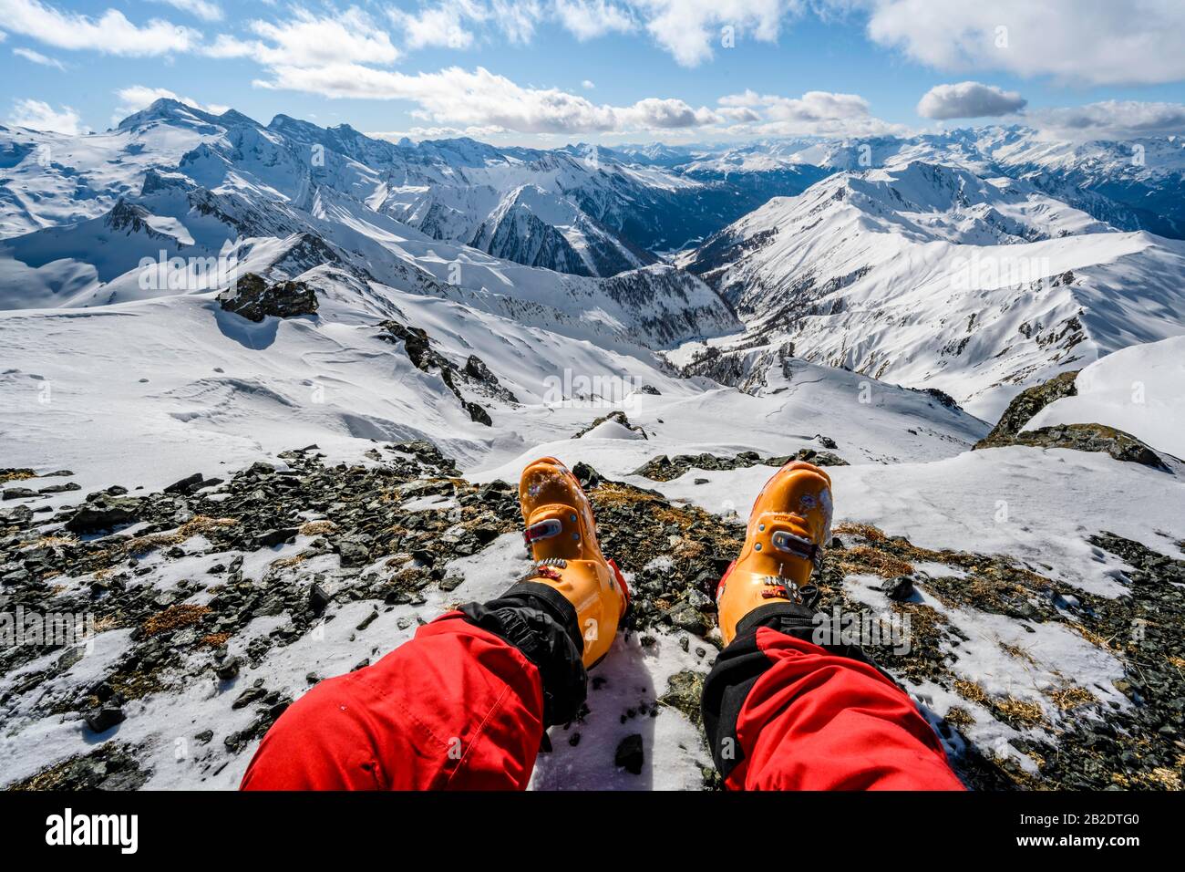 Vista dalla cima della Geierspitze, gambe con scarponi davanti a un panorama di montagna innevato, Wattentaler Lizum, Alpi Tuxer, Tirolo Foto Stock