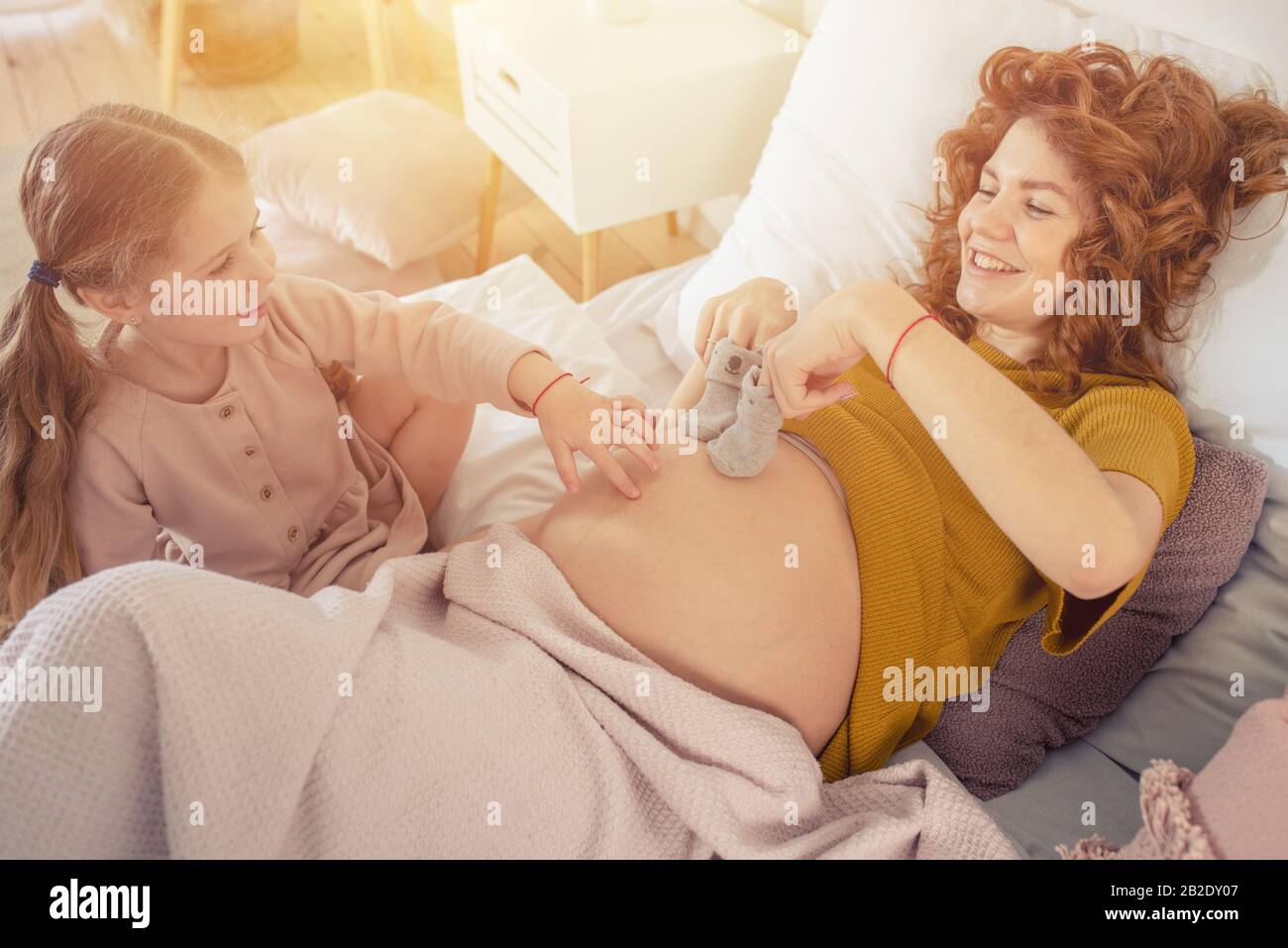 Mamma incinta gioca con sua figlia. Concetto di famiglia, gioia e gravidanza Foto Stock