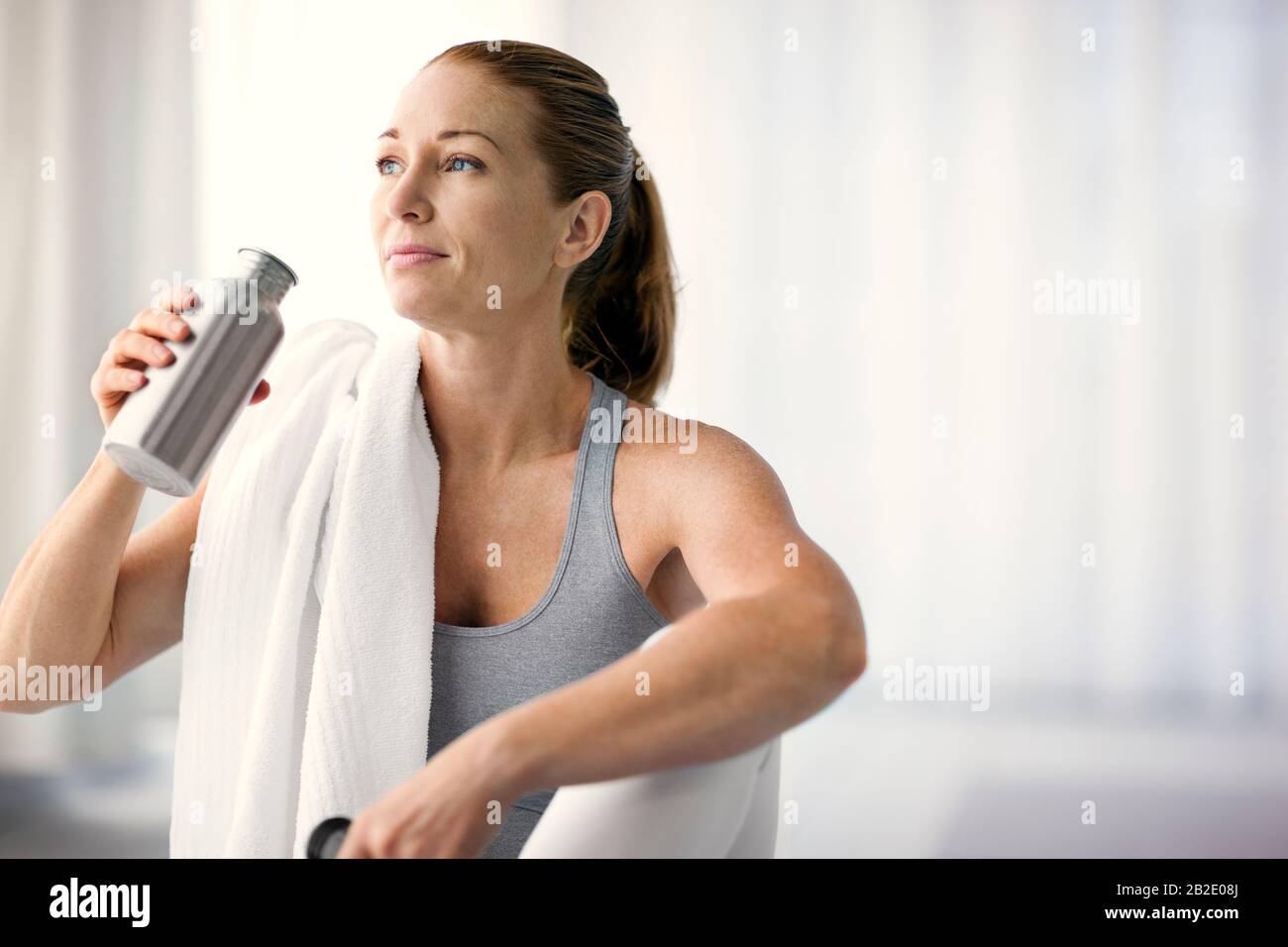 Donna adulta media che beve da una bottiglia d'acqua dopo l'esercizio Foto Stock