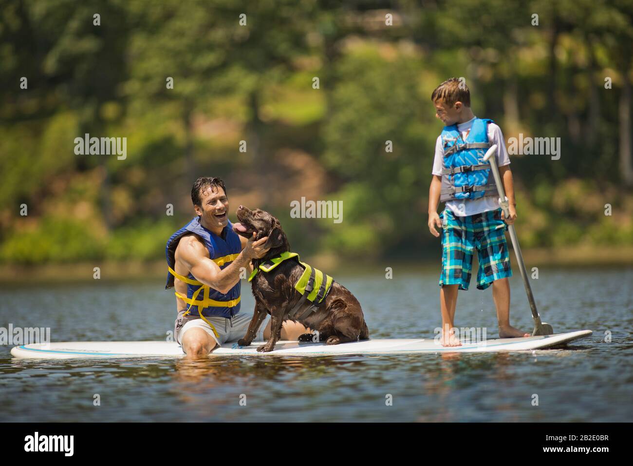 Padre e figlio che pagaia con un cane in un lago Foto Stock