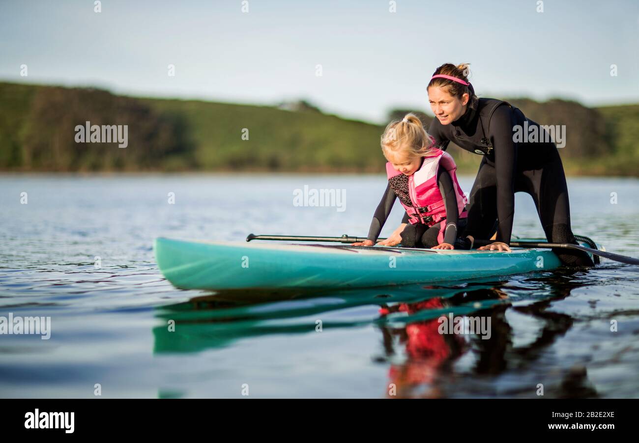 Una donna adulta e la sua giovane figlia pagaiano insieme su un lago Foto Stock